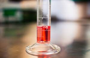 a graduated cylinder with red diesel fuel in it