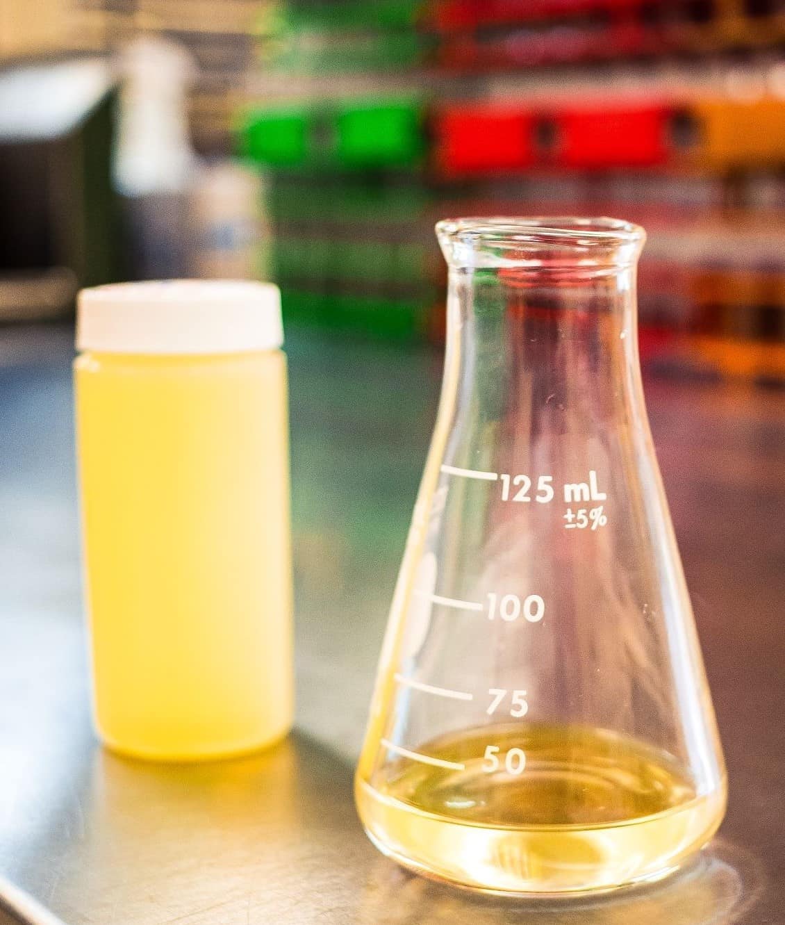 Yellow oil or fuel in a test kit bottle beside a beaker of oil