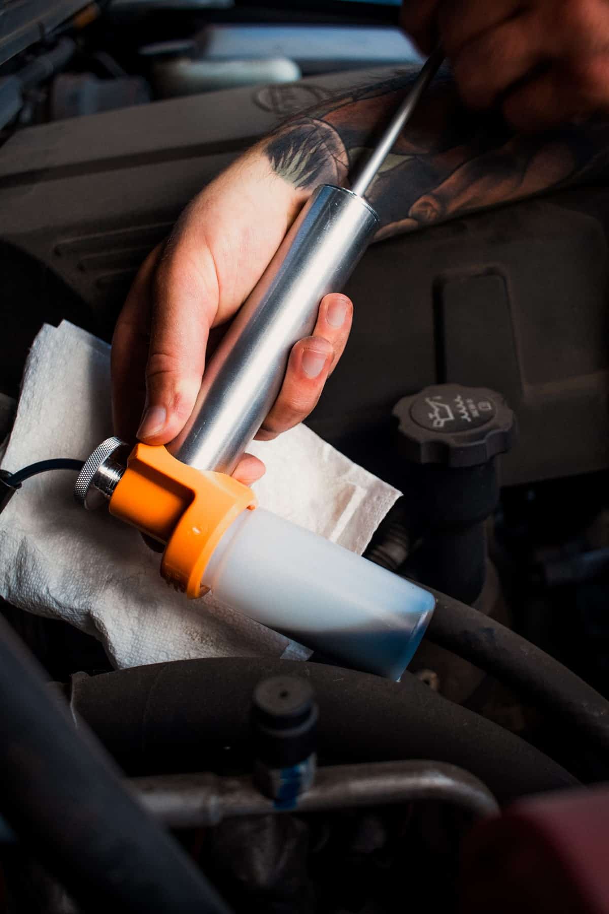 Close up of a quick-draw pump with used engine oil flowing through the tubing into the sample bottle