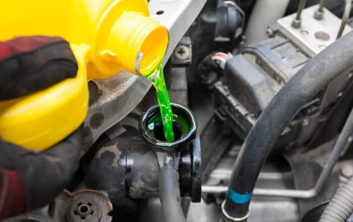 Green antifreeze pouring into the coolant reservoir in an engine