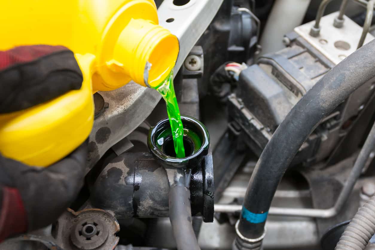 Green antifreeze pouring into the coolant reservoir in an engine