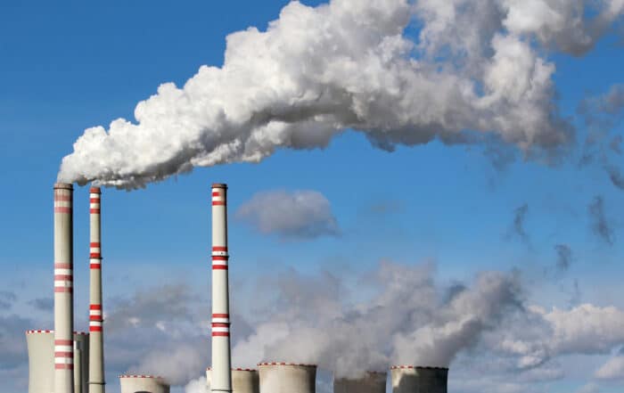 White smoke from factory smokestacks against a blue sky