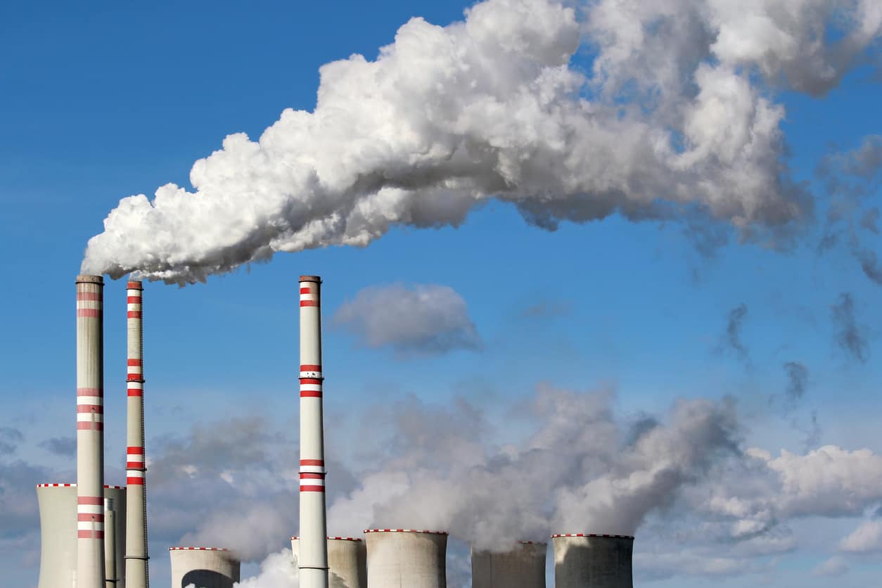 White smoke from factory smokestacks against a blue sky