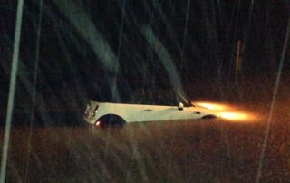 Ryan's Mini Cooper floating down a flooded street in the rain on a dark night, with the headlights shining under water. A sad sight indeed.