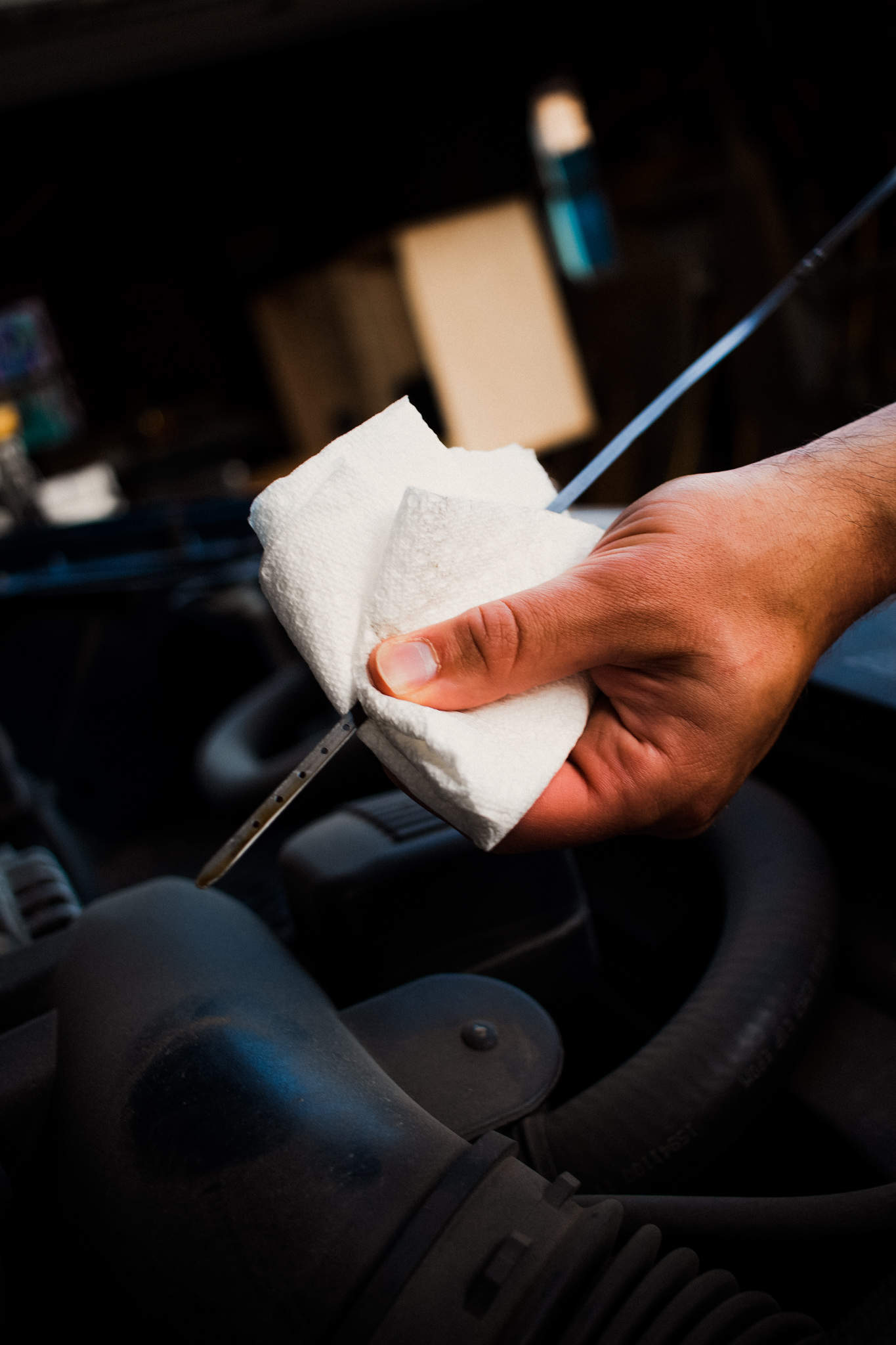 Close up of someone cleaning an engine dipstick with a paper towel