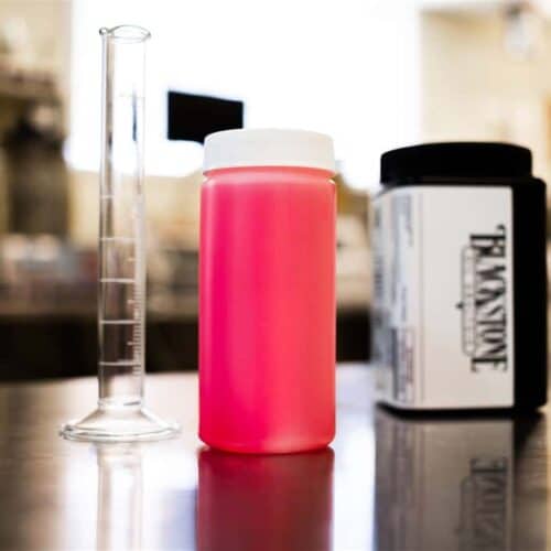 A red diesel fuel sample next to a Blackstone Laboratories kit and a graduated cylinder