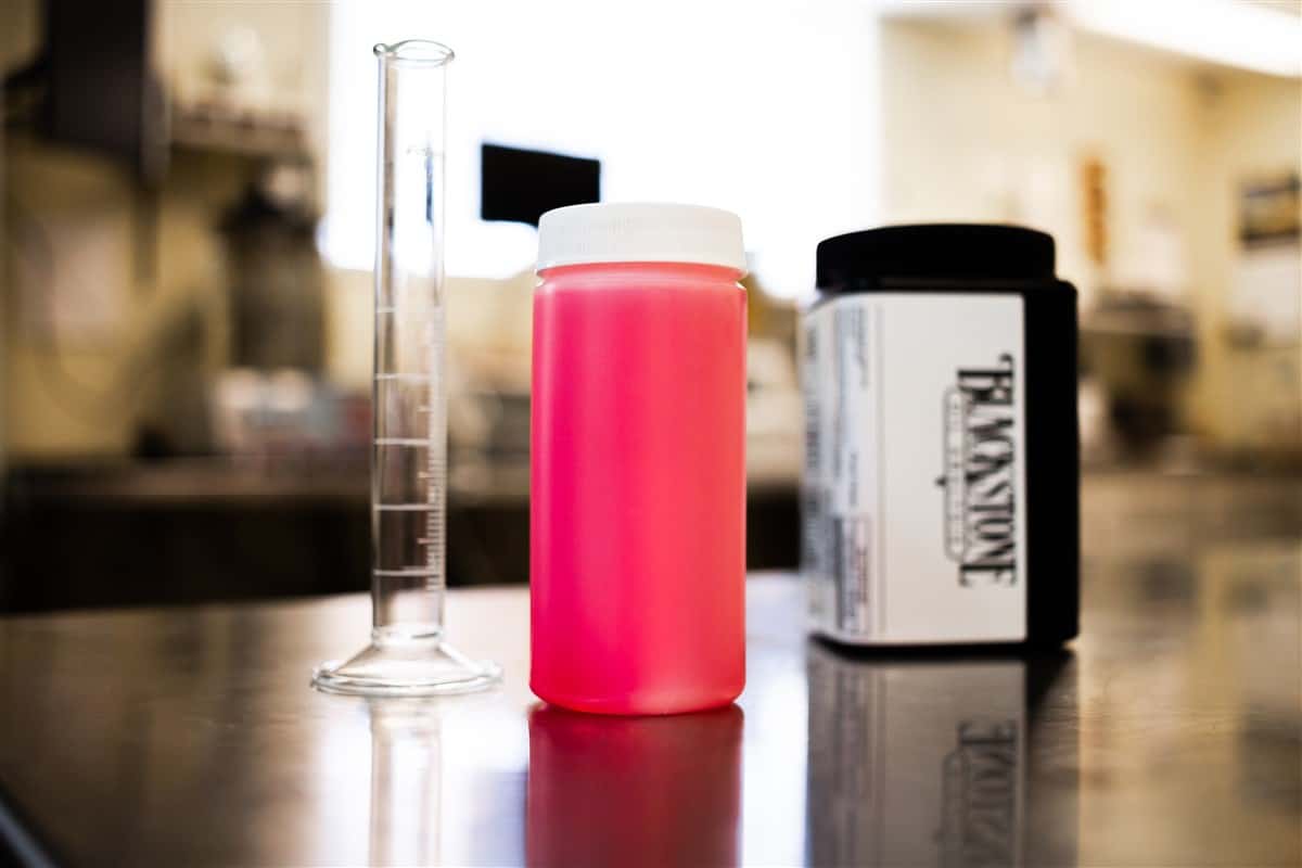 A red diesel fuel sample next to a Blackstone Laboratories kit and a graduated cylinder