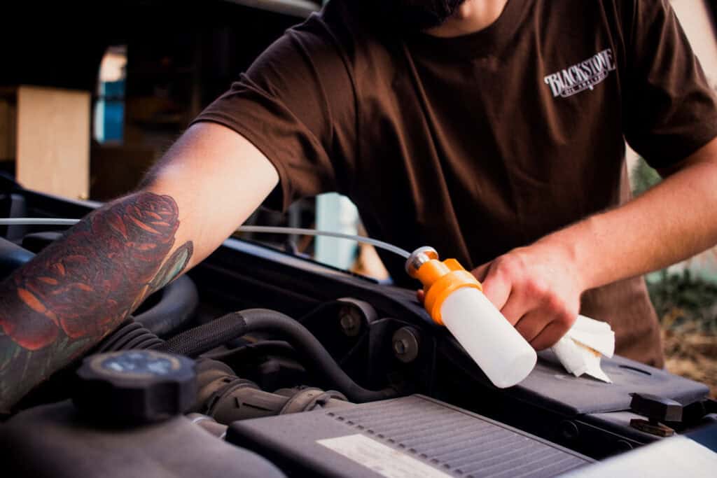 Close up of Blackstone Joe reaching into an engine to thread tubing down the dipstick to use with our sampling pump