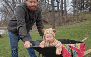 Image of quality control expert and senior analyst Luke, with his kid in a wheelbarrow