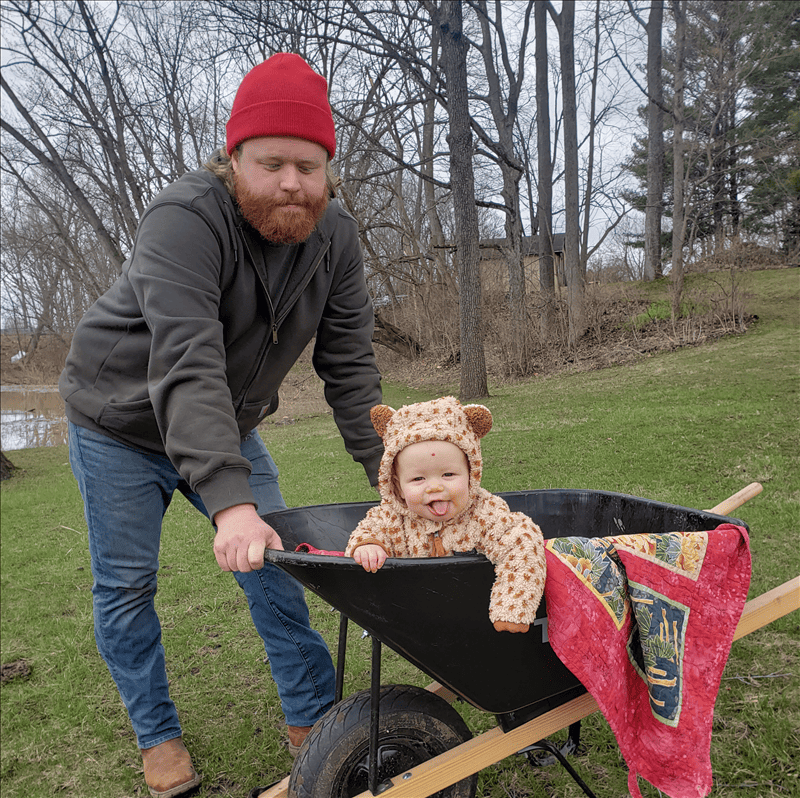 Image of quality control expert and senior analyst Luke, with his kid in a wheelbarrow